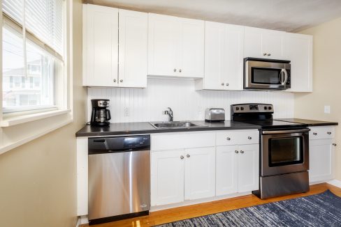 a kitchen with white cabinets and black counter tops.