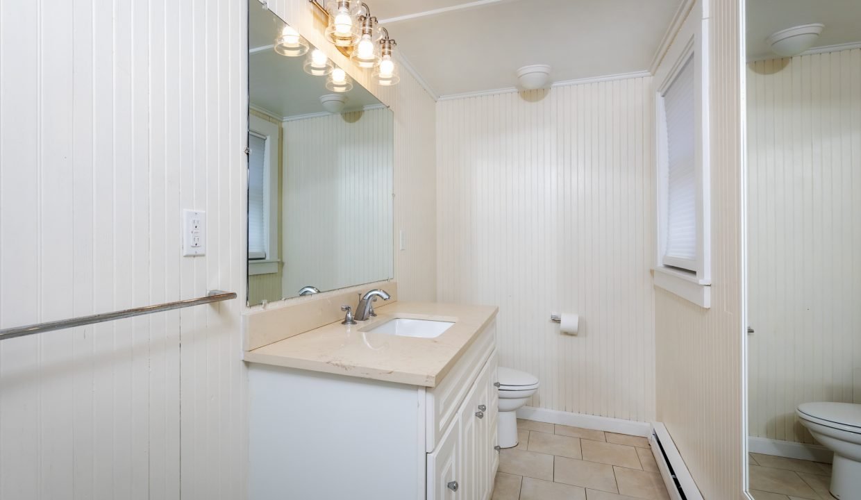 a bathroom with a sink, toilet and a mirror.