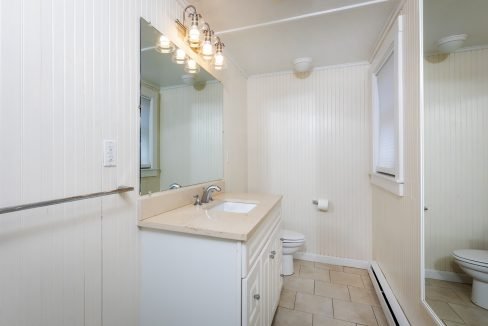 a bathroom with a sink, toilet and a mirror.