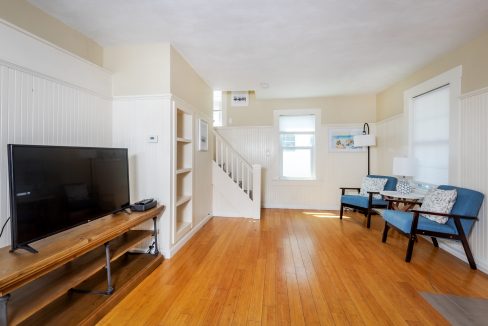 a living room with hard wood floors and a flat screen tv.