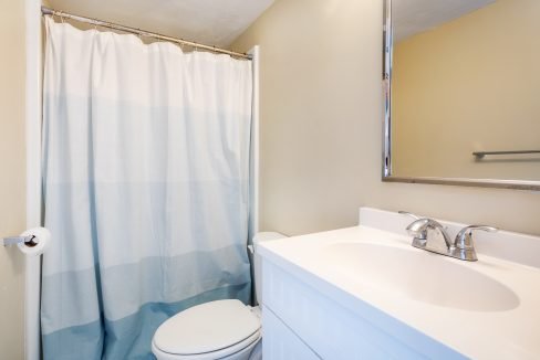a bathroom with a white toilet and a blue shower curtain.