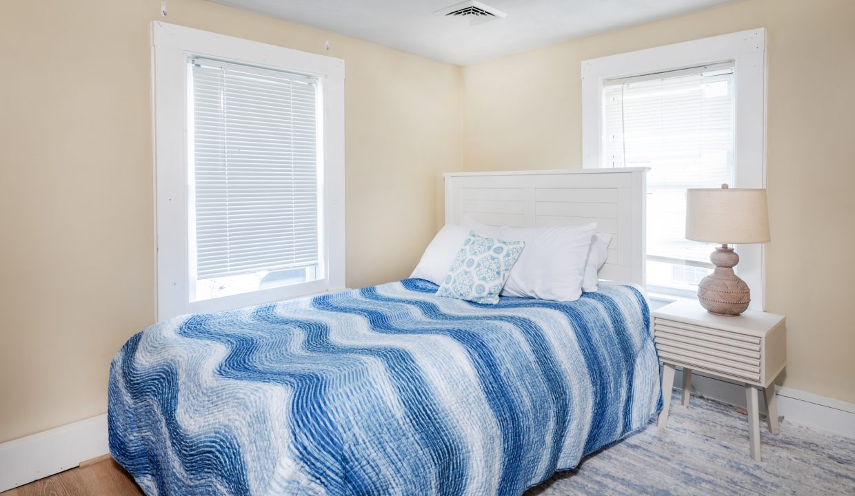 a bedroom with a bed and two windows.