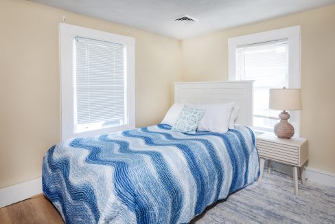 a bedroom with a bed and two windows.