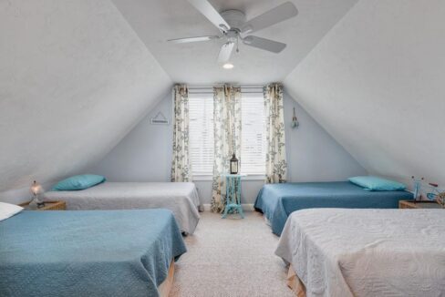 a bedroom with two beds and a ceiling fan.