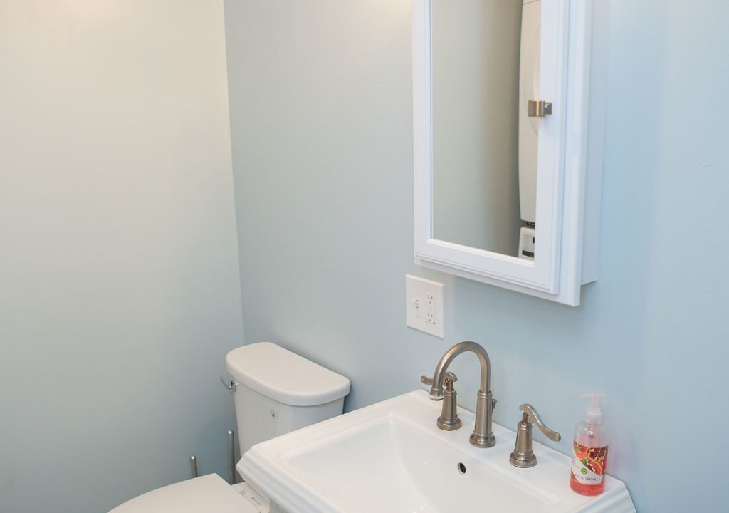 a bathroom with a toilet, sink and mirror.