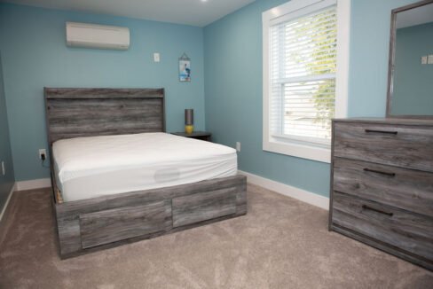 a bedroom with a bed, dresser, and window.