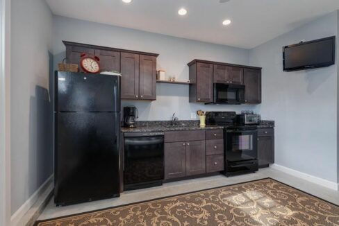 a kitchen with black appliances and a flat screen tv.