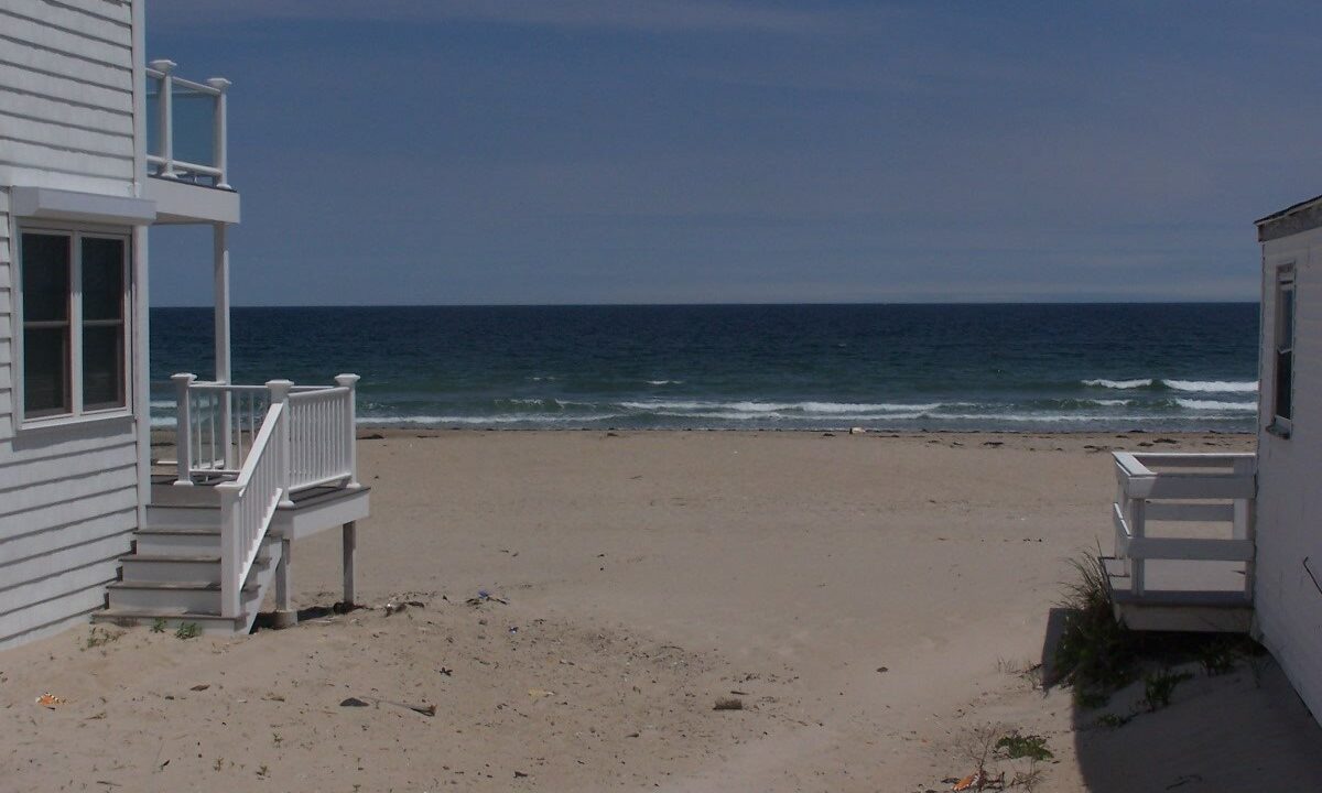 a house on the beach with stairs leading to the water.