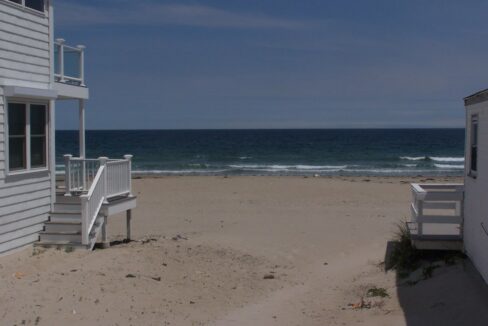 a house on the beach with stairs leading to the water.