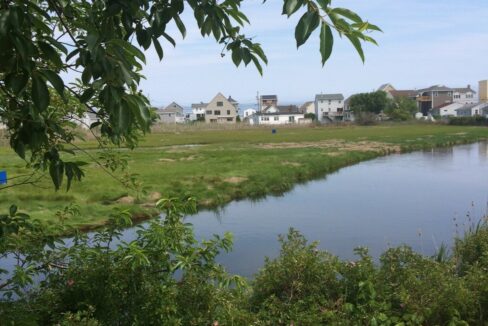 a body of water surrounded by a lush green field.