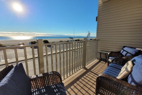 a balcony with wicker furniture and a view of the ocean.