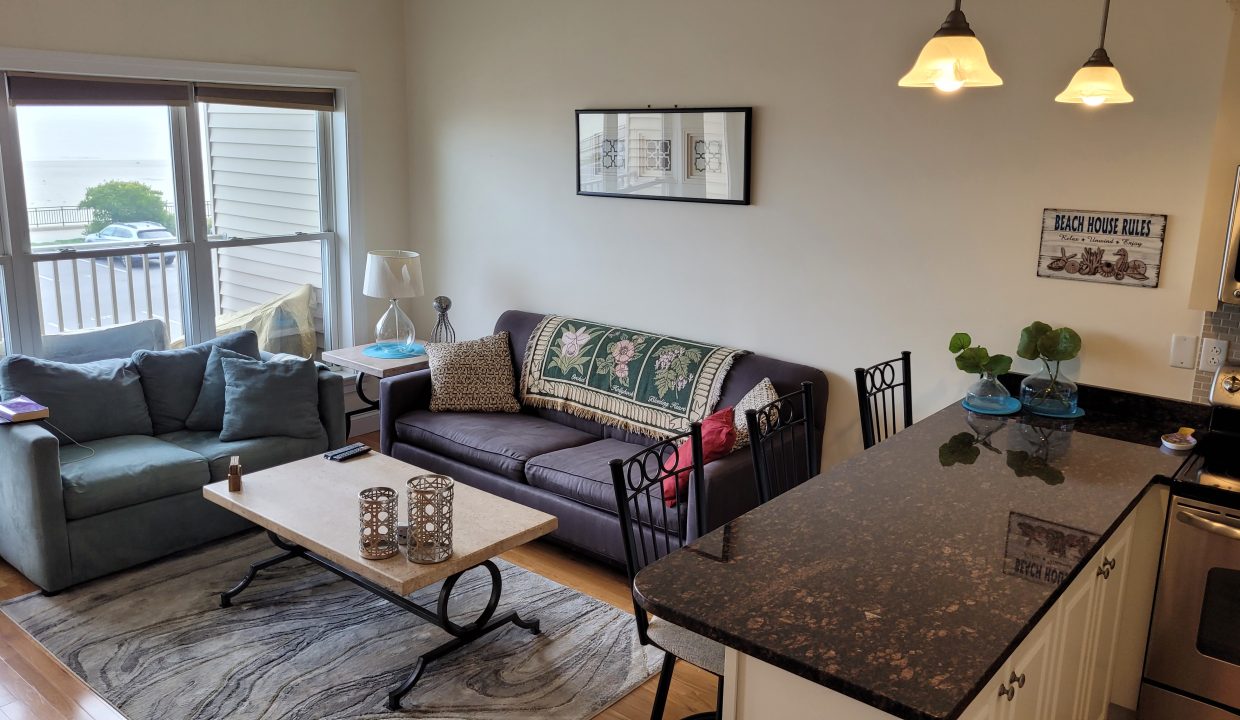 a living room filled with furniture next to a kitchen.