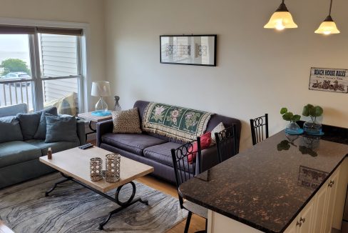 a living room filled with furniture next to a kitchen.