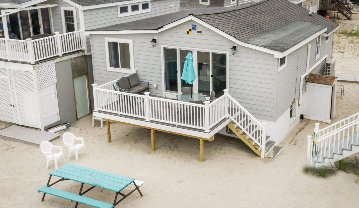 a beach house with a deck and a picnic table.