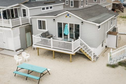 a beach house with a deck and a picnic table.