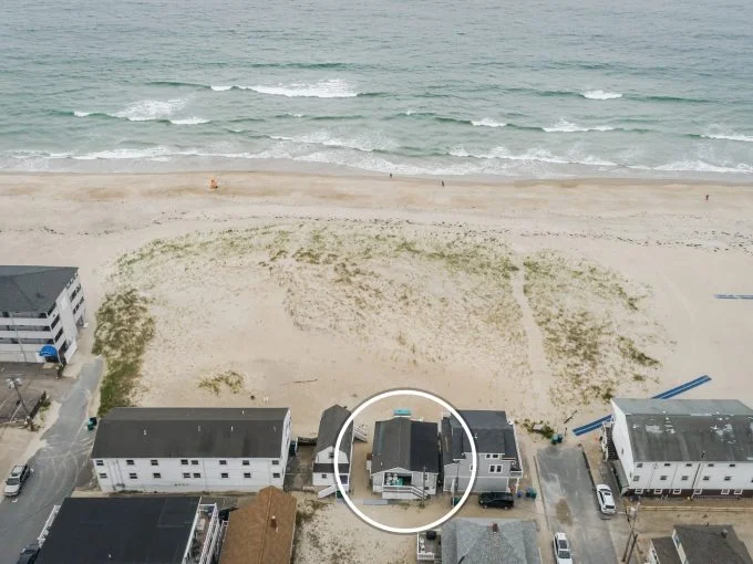 an aerial view of a beach with houses and the ocean in the background.