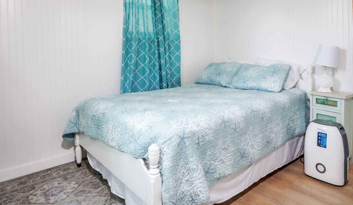 a bed with a blue comforter and a white night stand.