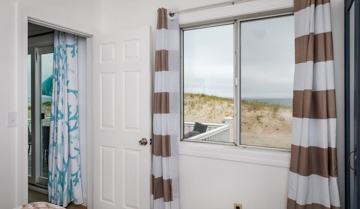 a bedroom with a large window overlooking the beach.