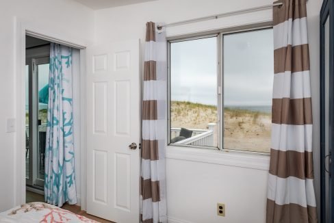 a bedroom with a large window overlooking the beach.