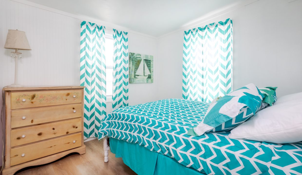 a bed room with a neatly made bed and a dresser.