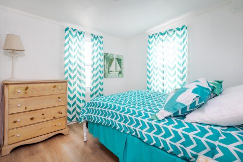 a bed room with a neatly made bed and a dresser.