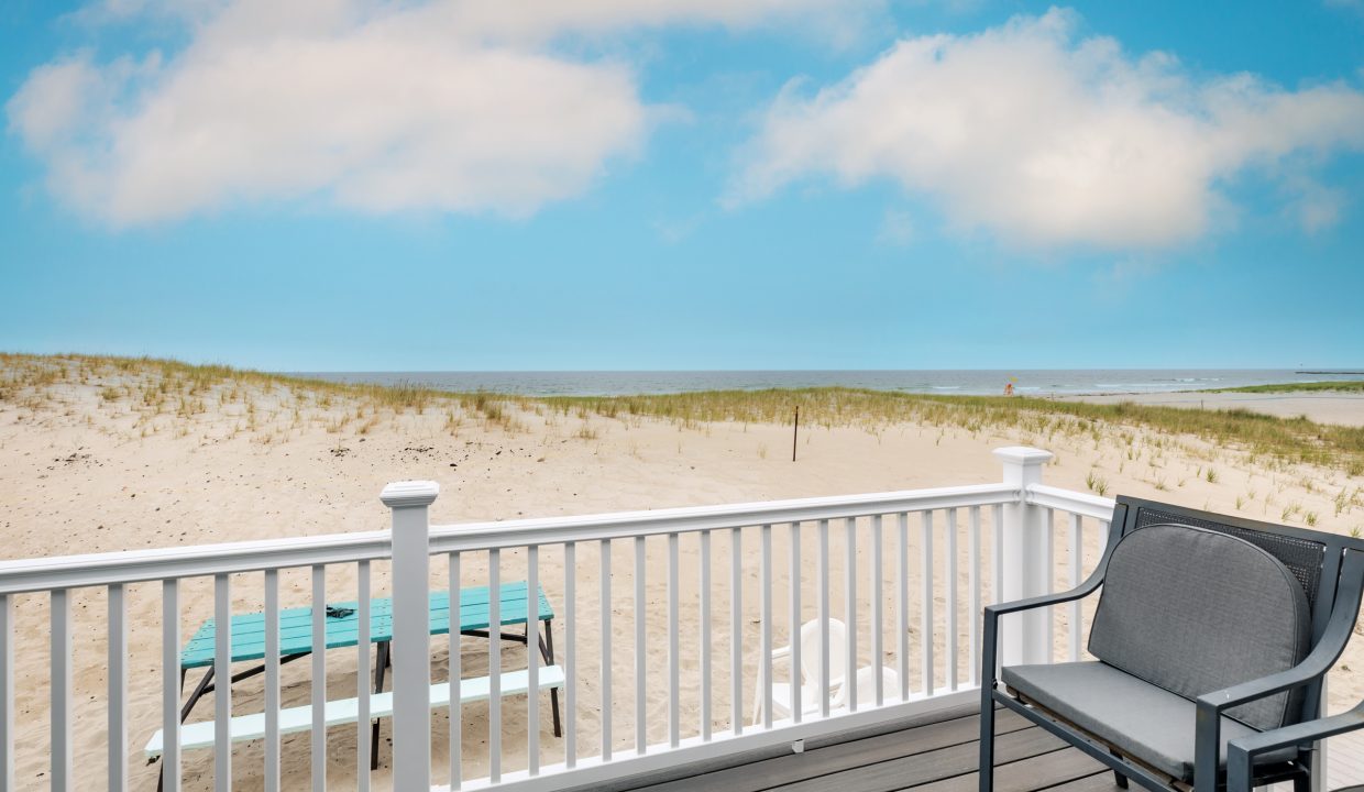 a chair and table on a deck overlooking the beach.