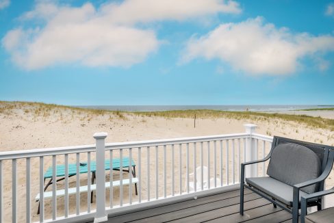 a chair and table on a deck overlooking the beach.