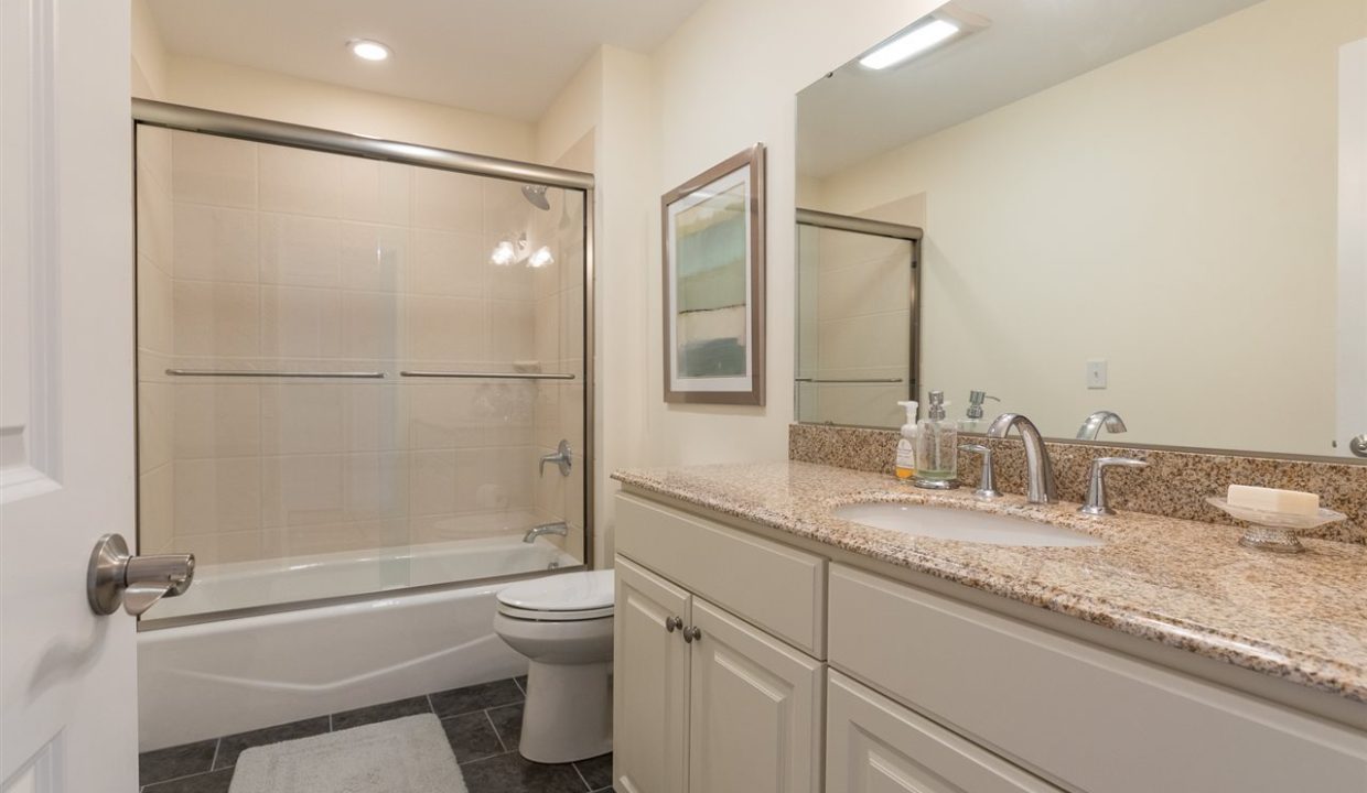 A bathroom with white cabinets and granite counter tops.