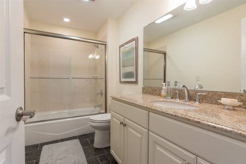 A bathroom with white cabinets and granite counter tops.