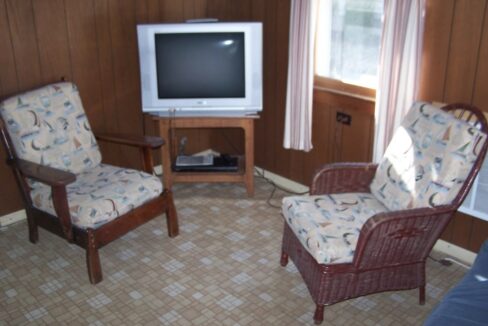 a living room with two chairs and a television.