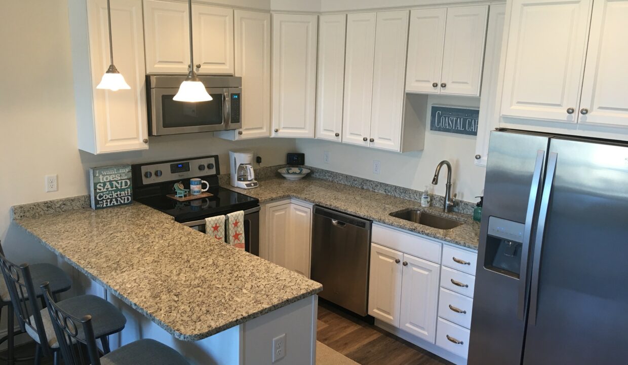 a kitchen with white cabinets and a silver refrigerator.