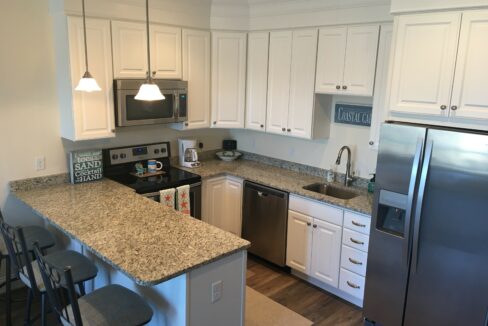 a kitchen with white cabinets and a silver refrigerator.