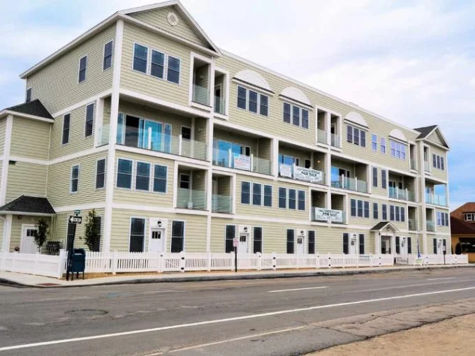 a two story apartment building on the corner of a street.