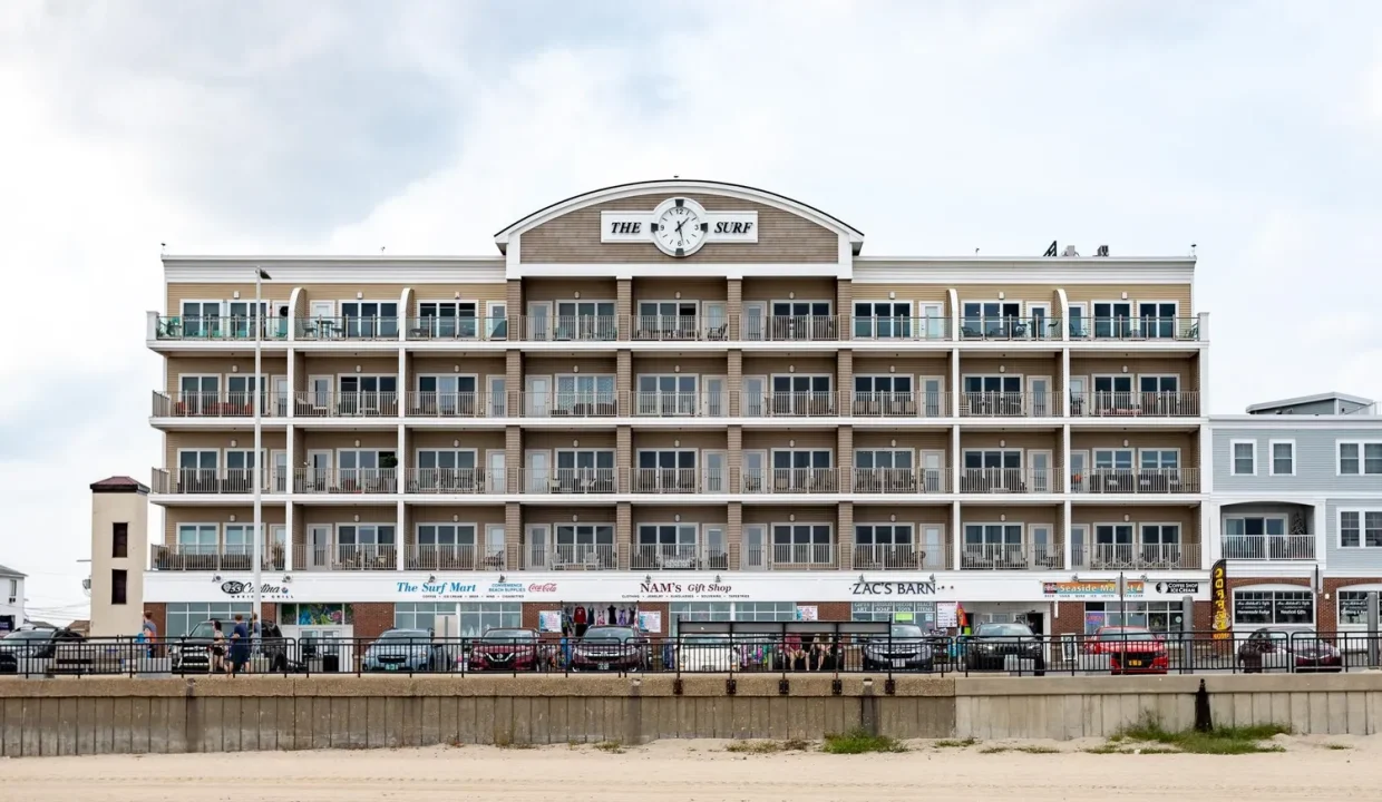 A large building on the beach with cars parked in front of it.