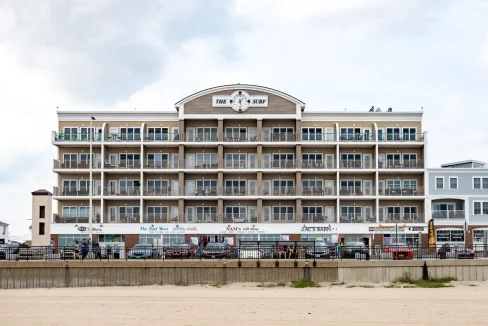 A large building on the beach with cars parked in front of it.