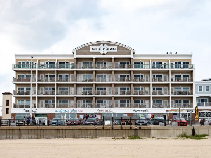 A large building on the beach with cars parked in front of it.