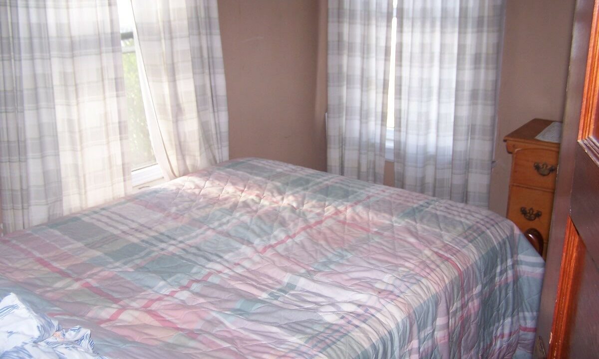 a bed with a plaid comforter in a bedroom.