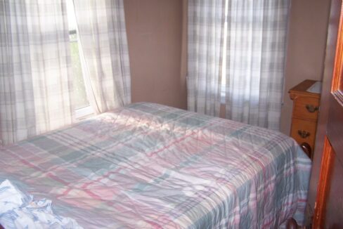 a bed with a plaid comforter in a bedroom.