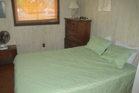 a bedroom with a bed, dresser, and window.