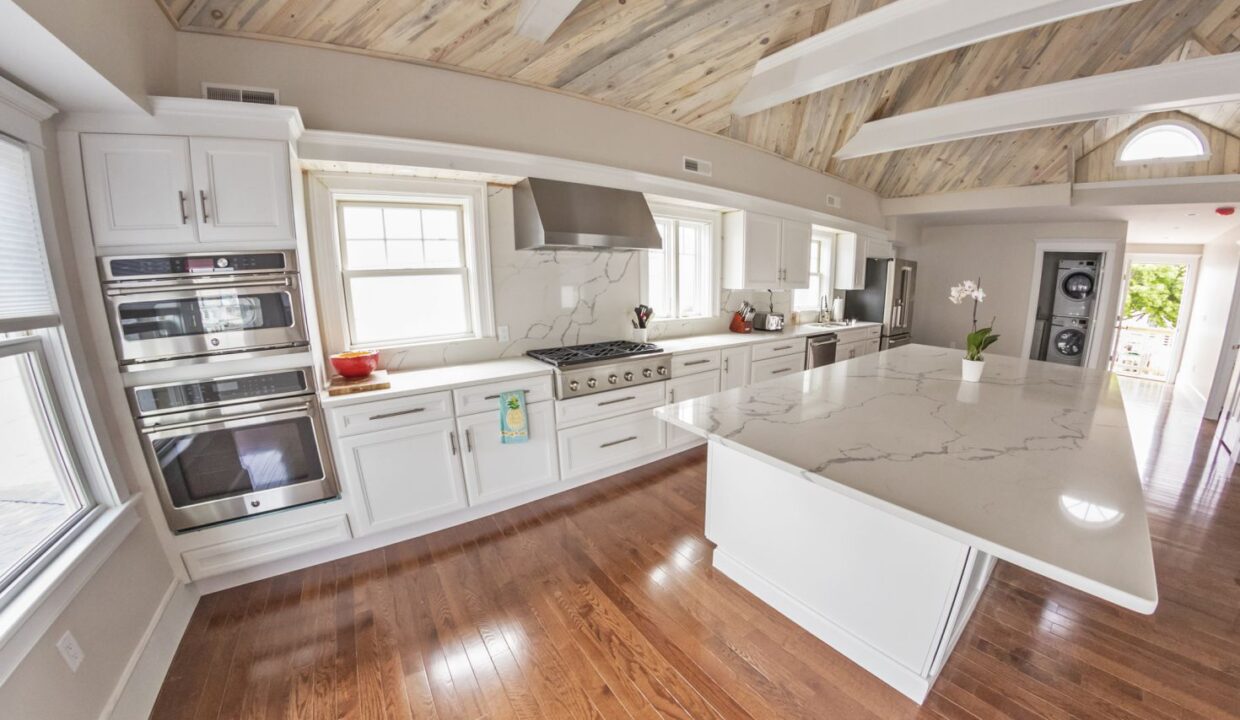a large kitchen with white cabinets and wood floors.