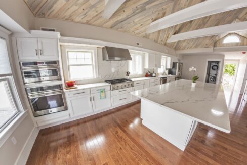 a large kitchen with white cabinets and wood floors.