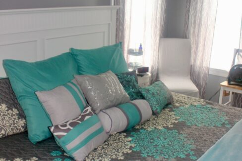 a bed with a blue comforter and pillows.