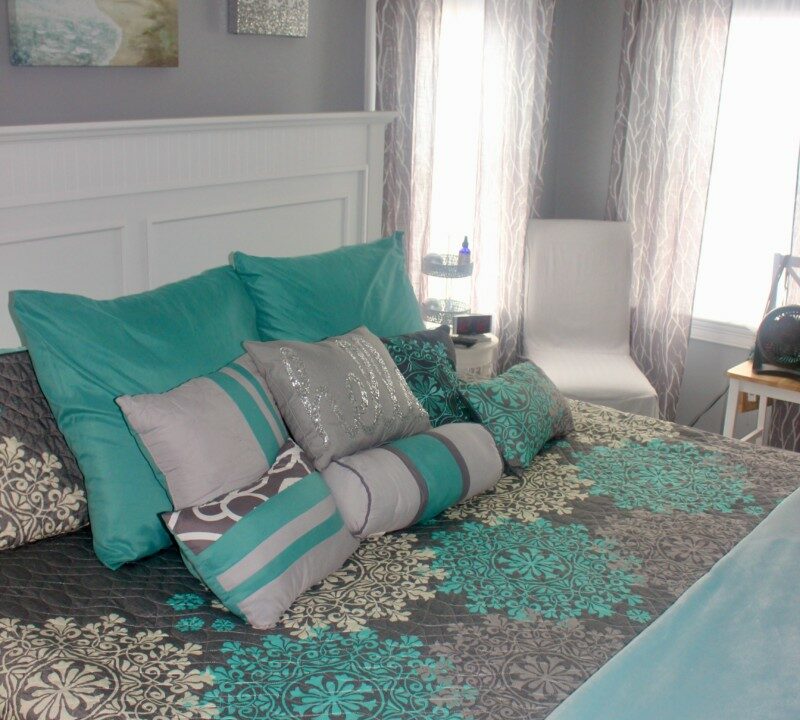 a bed with a blue comforter and pillows.