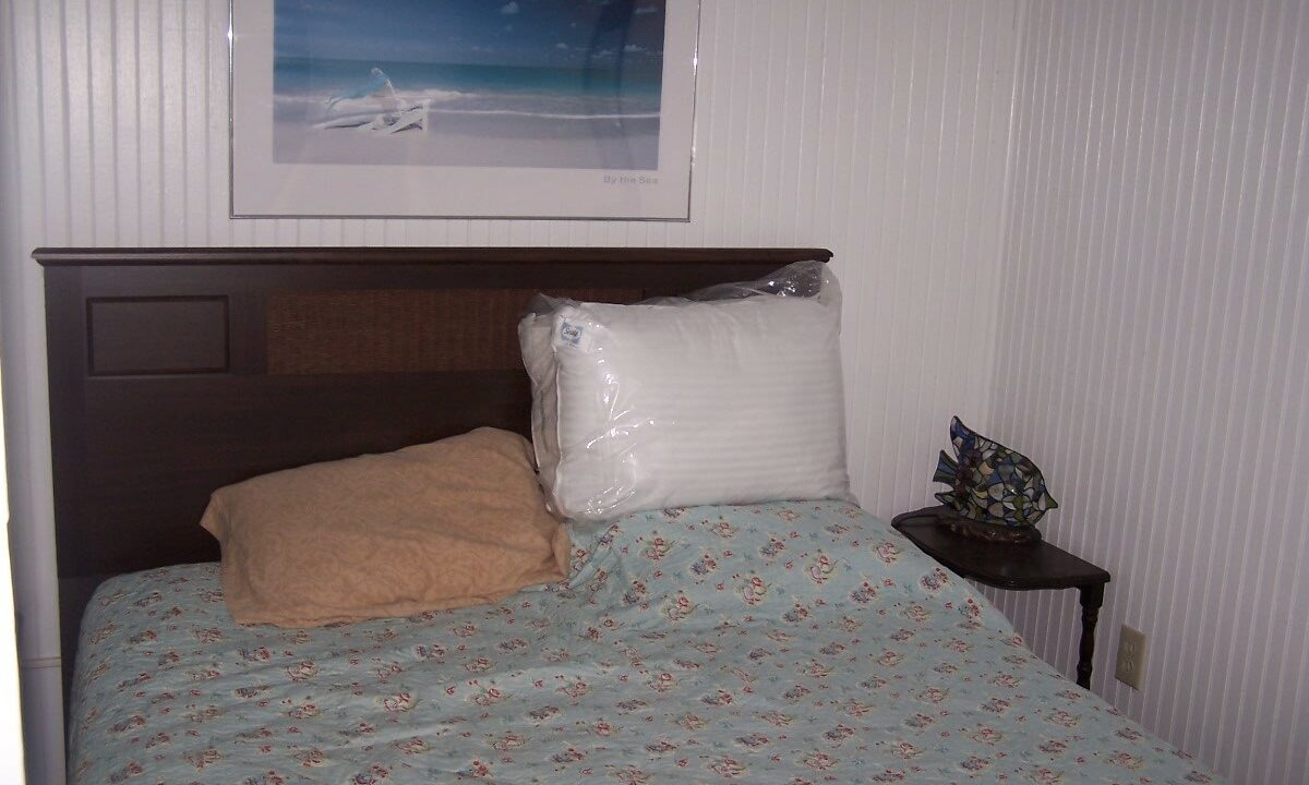 a bed with a blue bedspread and a picture on the wall.