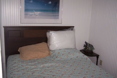 a bed with a blue bedspread and a picture on the wall.