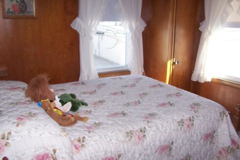 a teddy bear sitting on a bed in a bedroom.