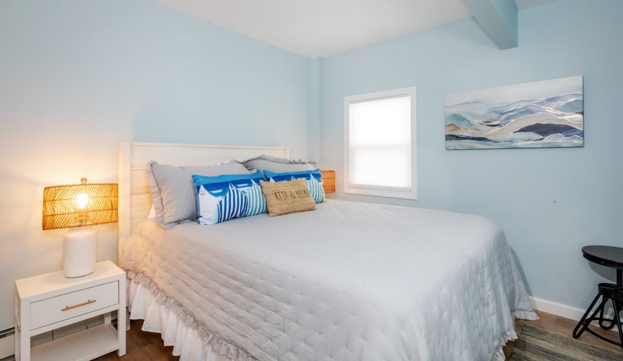 A bedroom with blue walls and a white bed.