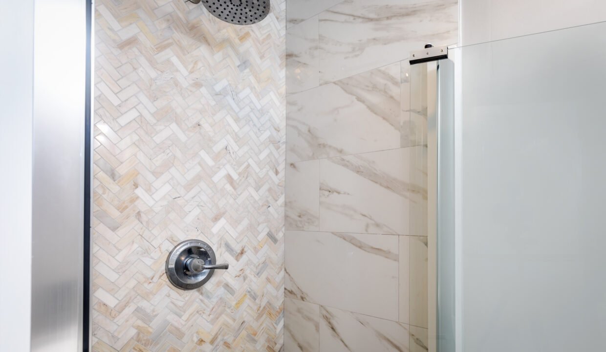 A shower with marble tile and a shower head.