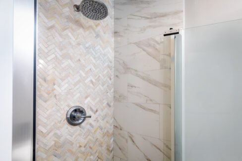 A shower with marble tile and a shower head.