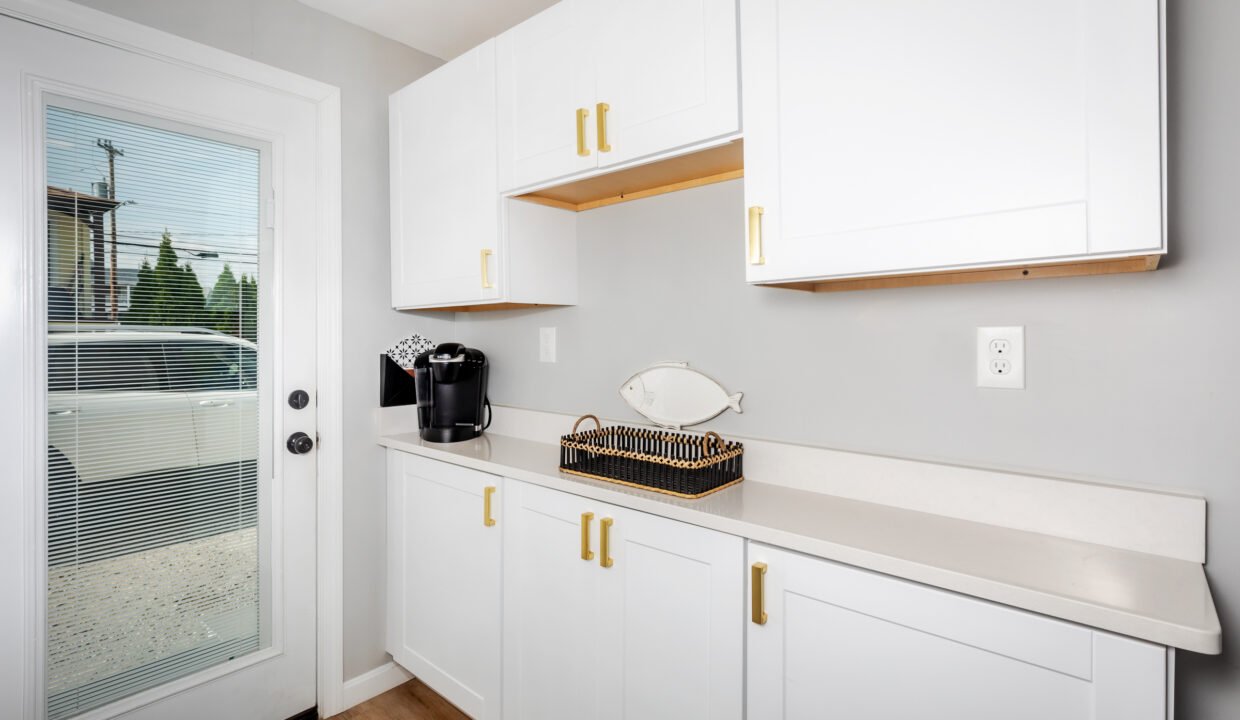 A kitchen with white cabinets and a door to the outside.